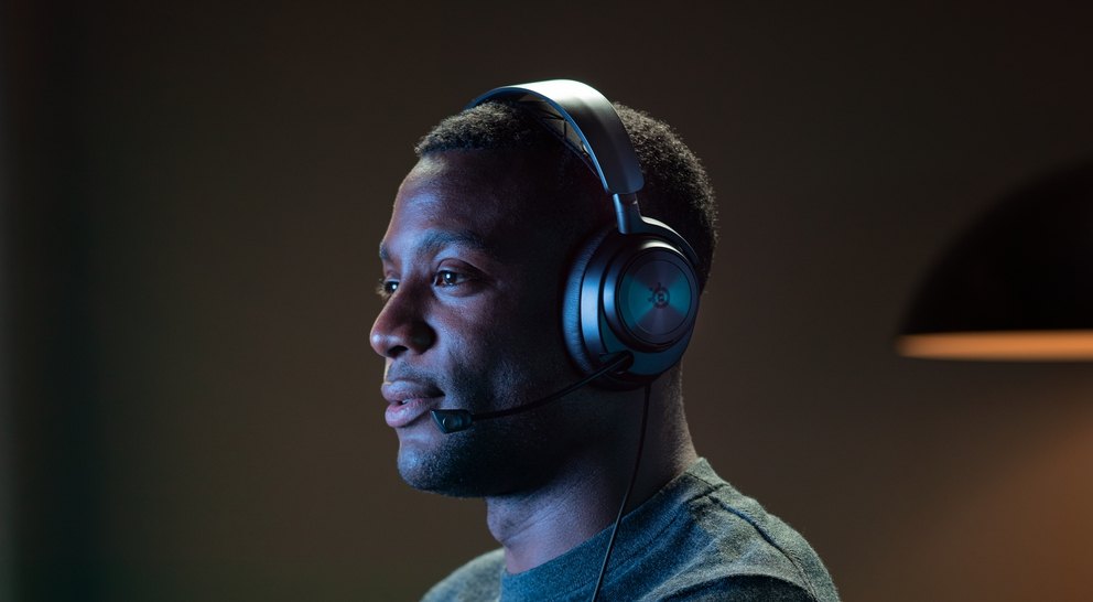 
 A person wears an Arctis Nova headset while playing a game.
 